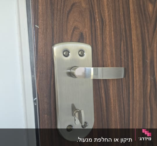ידית דלת מתכת על דלת עץ